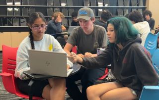 Three students working on laptop